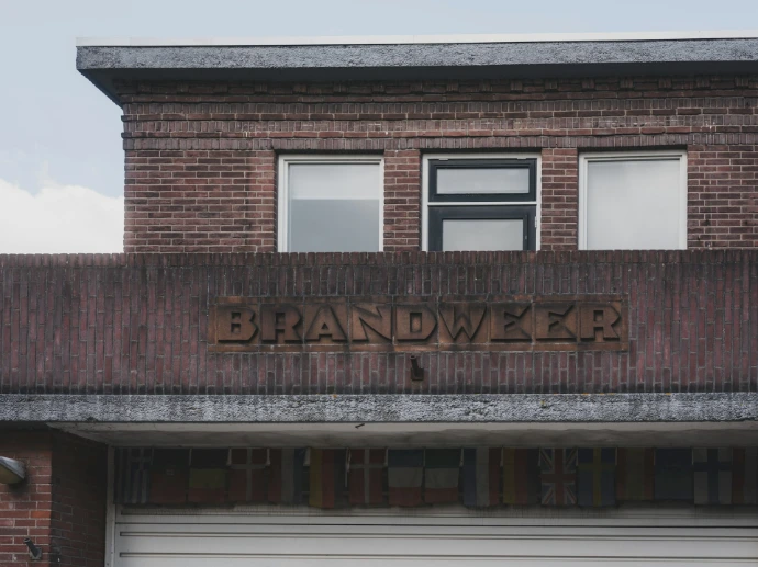 Brick building with "brandweer" sign above garage.